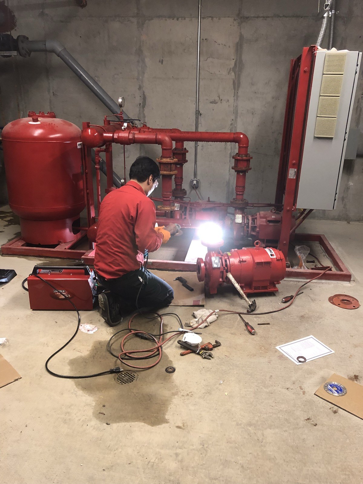 Technician welding beside a pump assembly