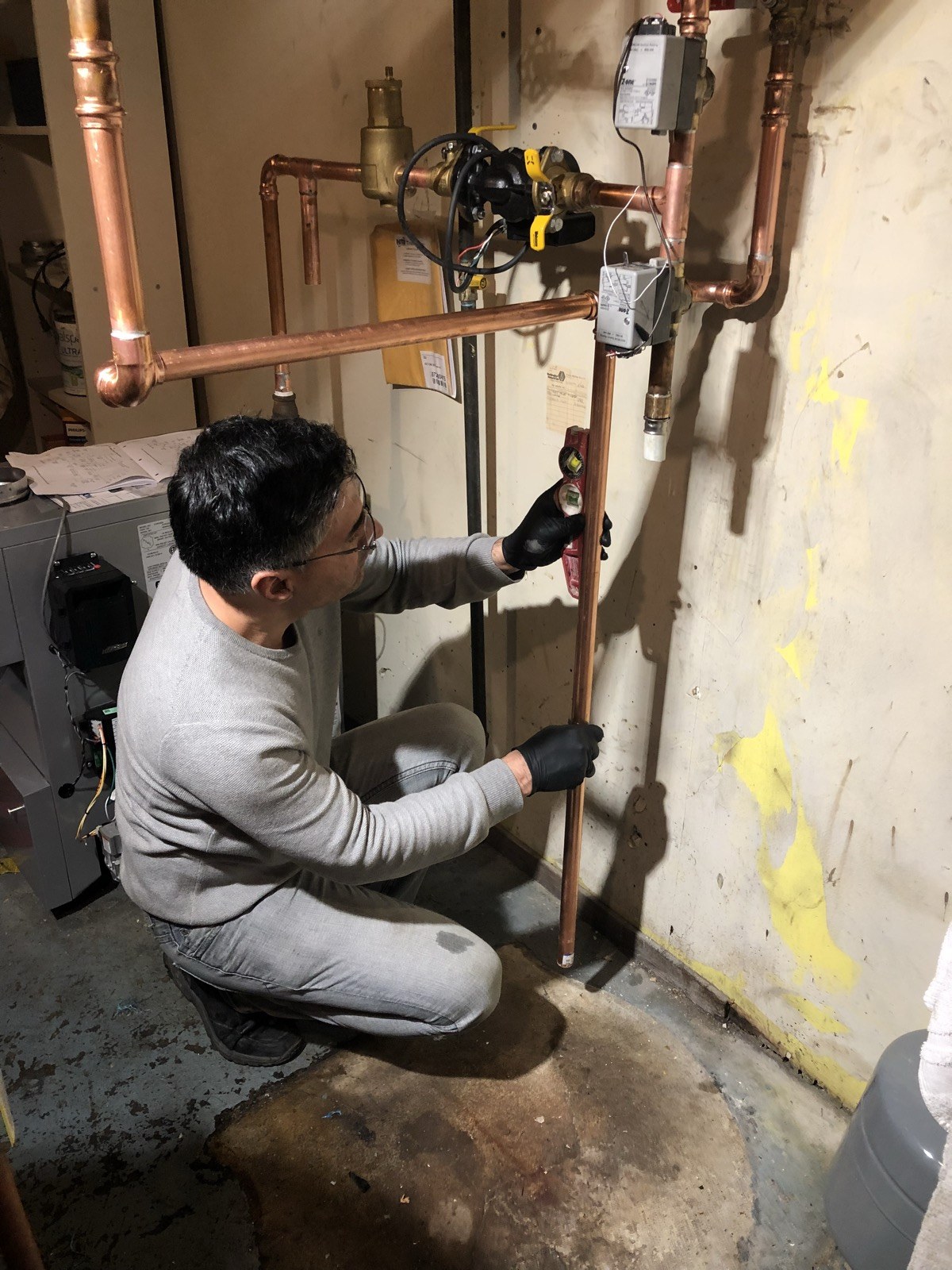 Technician checking copper heating-pipe alignment with a level