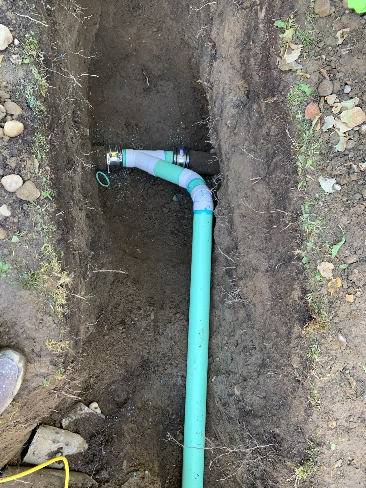 Green sewer pipe and coupling exposed in an outdoor trench