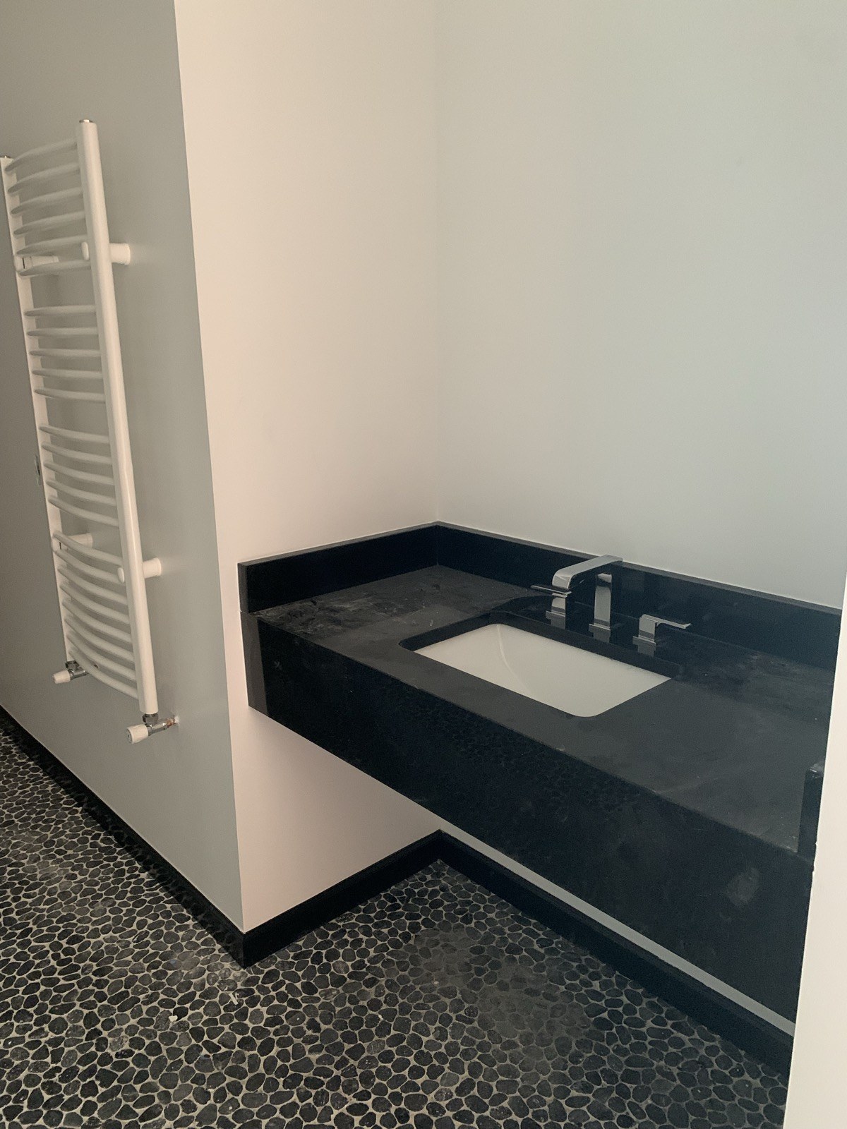 Undermount basin and chrome faucet in a black stone vanity